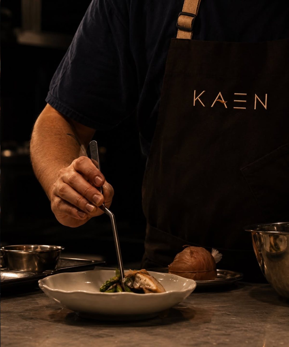 A KAEN cook plating a dish at the pass