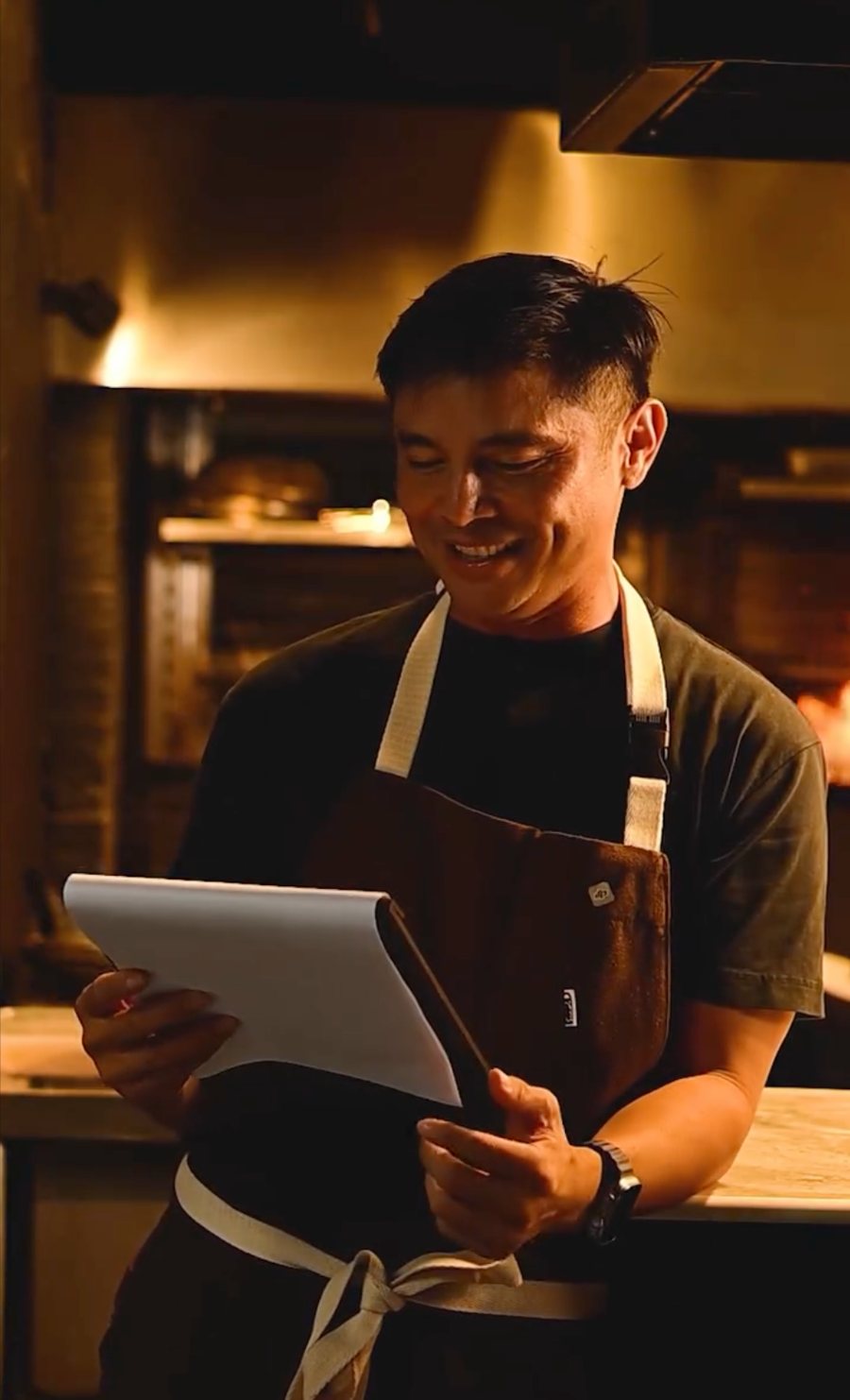 A restaurant team member standing near the kitchen pass